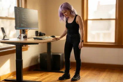 Mira standing at her standing desk in Dr. Martens boots on bare hardwood, looking down at her feet