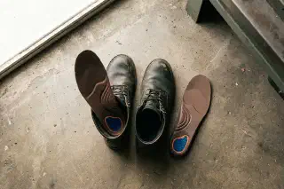New work boots beside supportive insoles on a hard floor