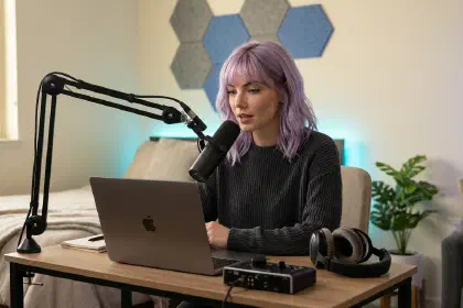 Mira at a small apartment desk speaking into a dynamic microphone on a boom arm