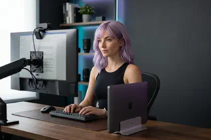 Mira at a docked laptop workstation with an external monitor and monitor-mounted webcam