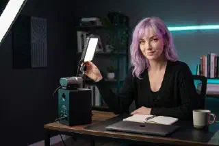 Mira at a desk with a compact soft light in a dark home office