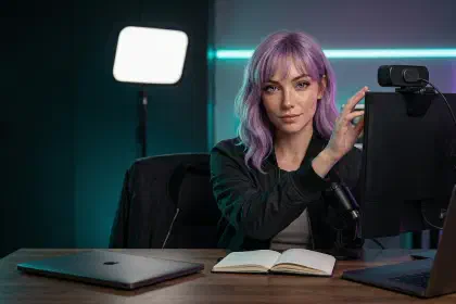 Mira at a creator desk with an external webcam, soft key light, and compact microphone setup